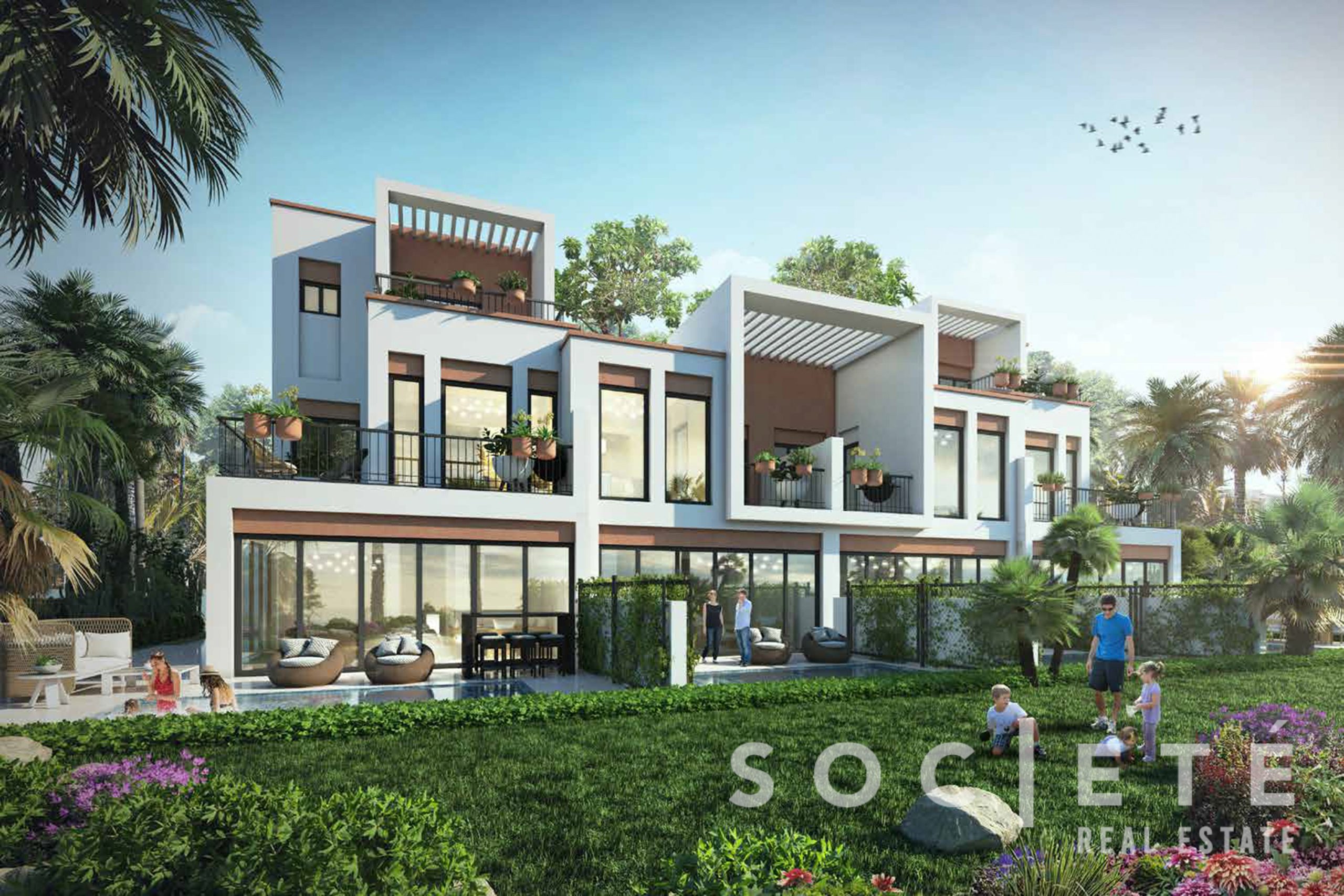 Modern white apartment building with balconies, outdoor terraces, and lush landscaping under a clear blue sky.