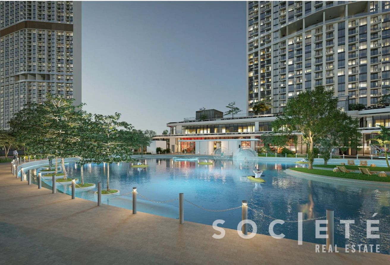 Modern residential complex with a large pool, trees, and high-rise buildings at dusk; SOCIÉTÉ Real Estate watermark.